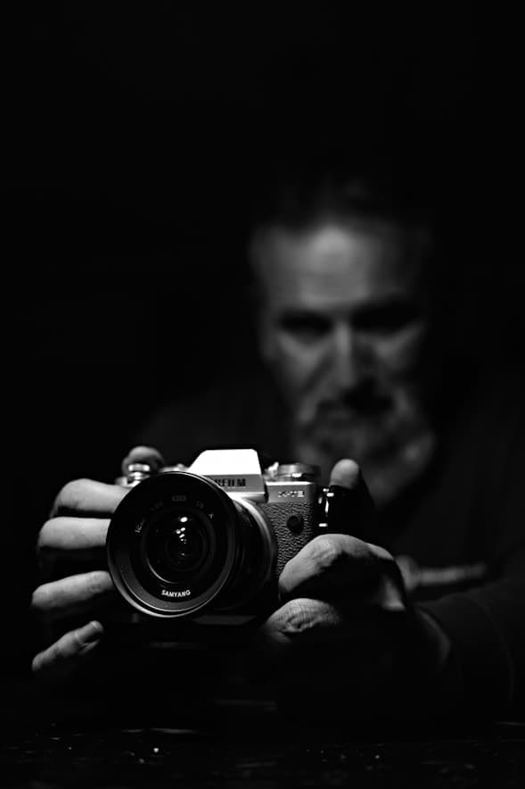 Photographer holding a Fujifilm camera in low light